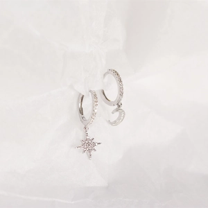 Macro shot of silver asymmetric moon and star hoop earrings with clear crystals