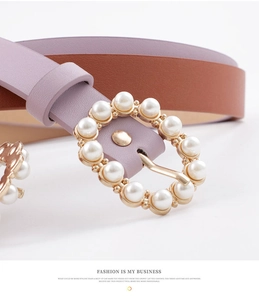 Detail of elegant gold round buckle with pearls on purple and brown leather belt