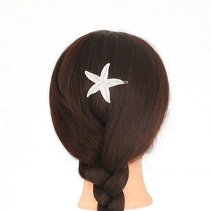 Detail shot of a silver starfish hair clip with sparkling beads on braided brown hair
