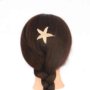 Close-up of a golden starfish hair clip elegantly worn on a dark brown braided hairstyle