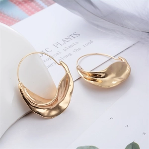 Detail of irregular wave-shaped gold earrings with liquid metal texture on card