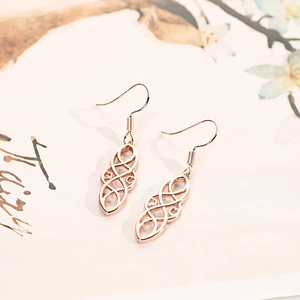 Detail of rose gold Celtic knot earrings with dual-layer hollow geometric metal pattern