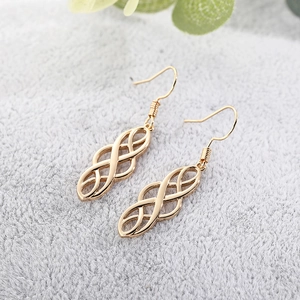 Detailed macro view of gold-tone Celtic drop earrings with intricate hollow-out patterns