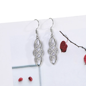 Detailed close-up of vintage hollow silver earrings with ornate geometric floral patterns