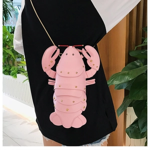 Pink lobster-shaped crossbody bag with golden studs and metal chain shown on model