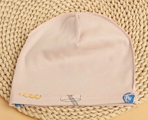 Detailed sewing of pink cotton baby hat with cute print on soft knitted fabric