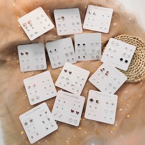 Close-up of mixed earring sets with stars and hearts on a decorative fabric background