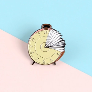 Creative alarm clock book enamel pin with yellow dial and brown casing on pastel background