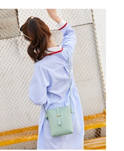 Detail of mint green mini crossbody phone bag with gold buckle on a model outdoors