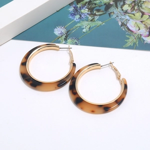 Close-up of leopard print acetate C-shape hoop earrings on a decorative background