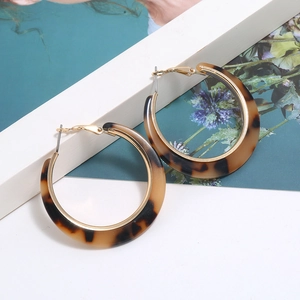 Macro detail of amber tortoiseshell pattern hoop earrings with gold metal fasteners