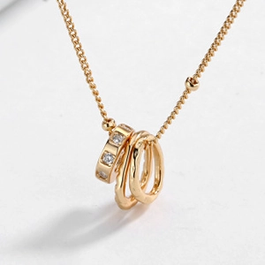 Detailed close-up of a golden triple-ring pendant necklace on a clean white background