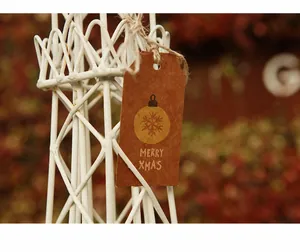 Detail of kraft paper Christmas gift tag with gold snowflake globe and jute twine
