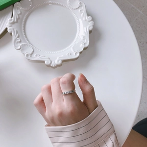 Close-up of silver FAITH cross ring on finger with elegant table setting background