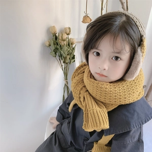Detail of child wearing ginger knit scarf and plush earmuffs against soft background