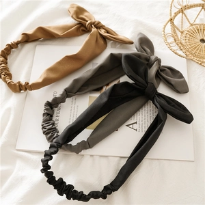 Detailed flat lay of soft rabbit ear elastic headbands in camel, grey, and black colors