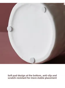 Detail of white ceramic vase base with non-slip pads to protect furniture surfaces