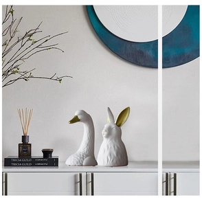 Detail of elegant white ceramic swan and rabbit vases with golden accents for home decor