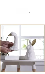 Detail of hand-held ceramic animal vases with matte white texture and gold accents