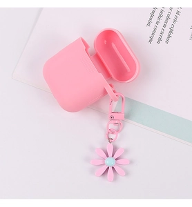 Pink silicone AirPods case detail with floral charm and metal carabiner on white desk