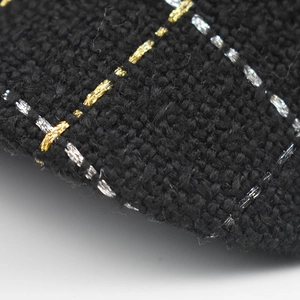 Détail du tissu en tweed noir avec des fils métalliques or et argent sur un béret