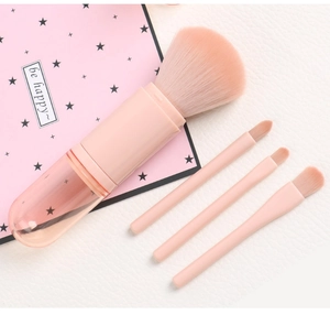 Detail of 4-in-1 retractable pink makeup brush set with synthetic bristles on white texture