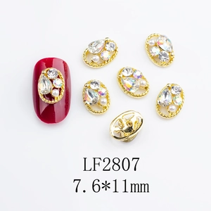 Close-up of golden oval hollow nail charm with teardrop zircon and small pearl detail