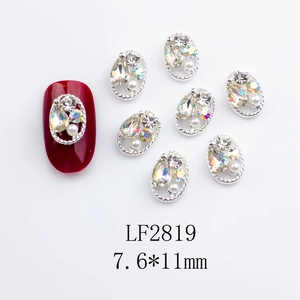 Detail of silver oval hollow nail charms with opal rhinestones and pearls on red nails