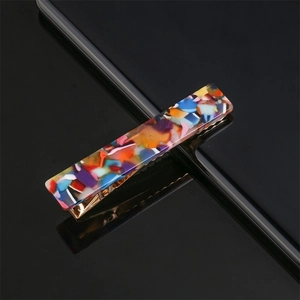 Close-up of a colorful mosaic pattern hair clip with a gold metal duckbill base