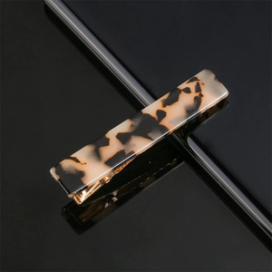 Close-up of a rectangular leopard print acetate hair clip with golden metal base