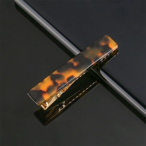 Macro detail of tortoiseshell acrylic hair clip with a gold metal fastener and marbled pattern