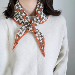 Nahaufnahme eines Strickschals mit Hahnentrittmuster in Orange und Braun am Modell