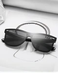 Close-up of black oversized flat top sunglasses featuring silver square metal hinge detail