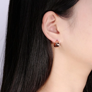 Close-up of polished rose gold stainless steel hoop earring worn on woman's ear