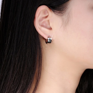 Close-up of polished silver stainless steel hoop earring worn by a model with hair