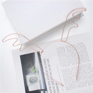 Detail of rose gold antler headband on minimalist white background with decorative candles