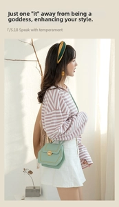Detail of light green crossbody bag featuring a hexagonal flap and golden twist lock