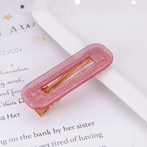 Close-up of a pink glitter acrylic hair clip with a gold metal duckbill base