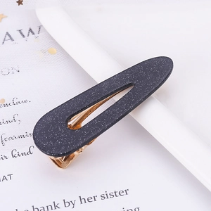 Macro detail of tear-shaped blue glitter hair clip with metallic gold base