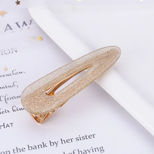 Close-up of a teardrop-shaped hair clip with sparkling gold glitter on a mesh background