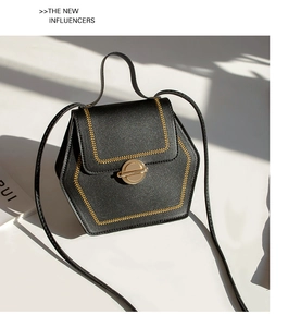 Detail of black geometric crossbody bag with golden embroidery and metal twist lock
