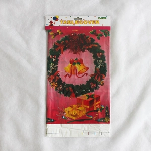 Détail d'une nappe de Noël rouge en plastique avec motifs de cloches et de couronnes