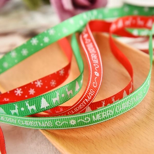 Macro shot of red and green Christmas ribbons with Merry Christmas print on a wooden tray
