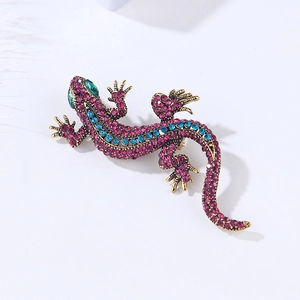 Macro detail of lizard brooch featuring pink and blue crystals on a golden metal base