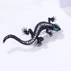 Macro shot of silver lizard brooch featuring deep blue rhinestones and green crystal eyes