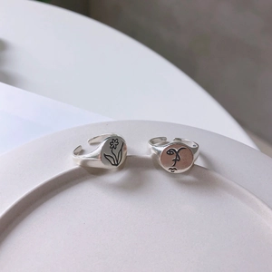 Close-up of 925 sterling silver adjustable rings with floral and face relief patterns