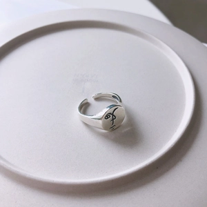 Macro detail of minimalist S925 silver ring featuring an abstract face engraving