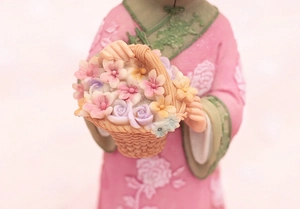 Close-up of a vintage girl figurine holding a colorful flower basket with detailed texture