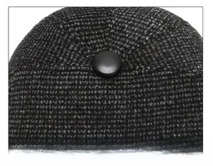 Macro shot of tweed flat cap crown featuring black leather button and reinforced stitching