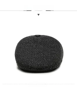 Close-up of a dark grey tweed flat cap for men with detailed herringbone texture and top button